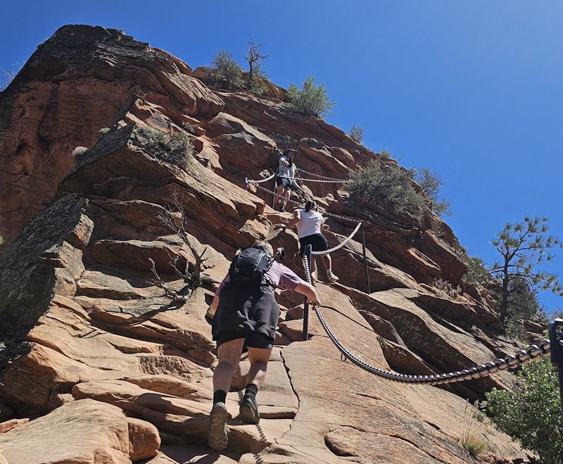 A hiker using the chains on the narrow spine of Angels Landing.