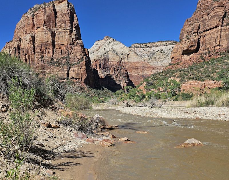 A hiker soaking their feet in the clear water of the Virgin River.